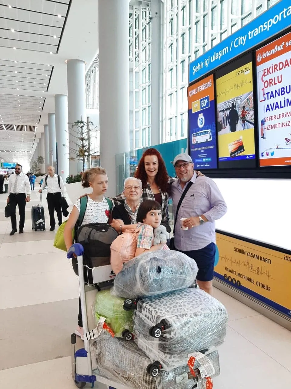 Family travelling through an airport terminal with their luggage
